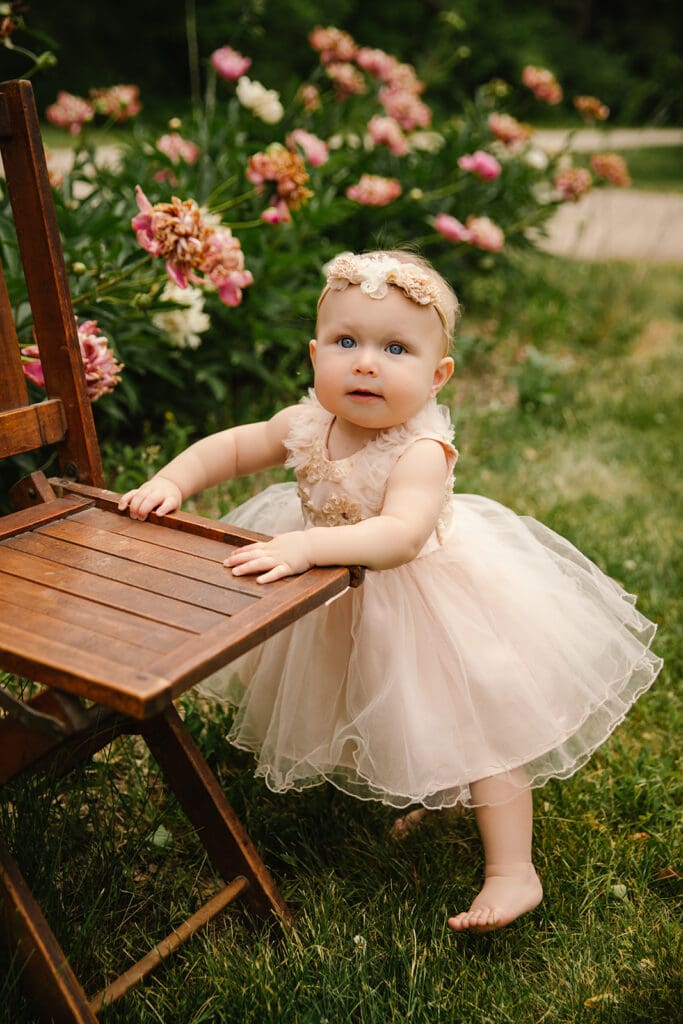 First year child milestone photo session with little girl in a pink tulle dress standing in a butterfly garden at a local park.