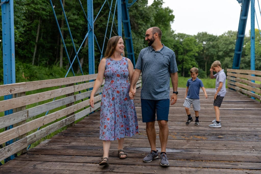 Eastern Iowa family photo session capturing mom and dad holding hands looking at each other with two kids following them.