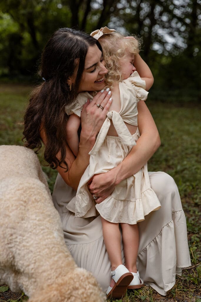 Candid moment of mom and toddler hugging during outdoor family photos near North Liberty, Iowa.