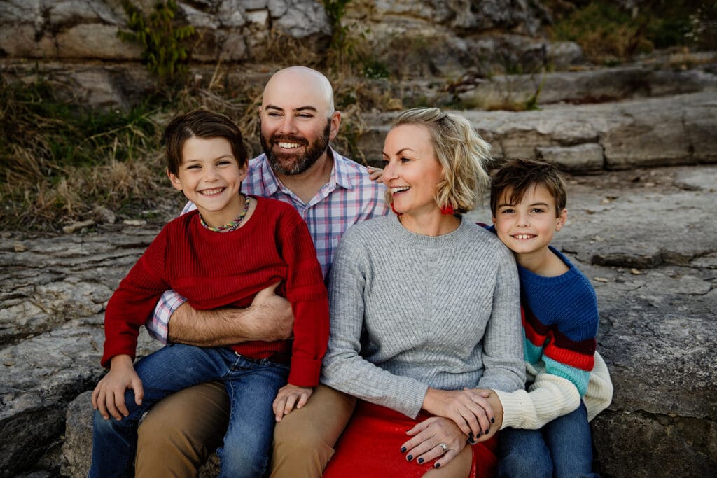 Family of 4 laughing together during a photo session near a lake in Eastern Iowa.